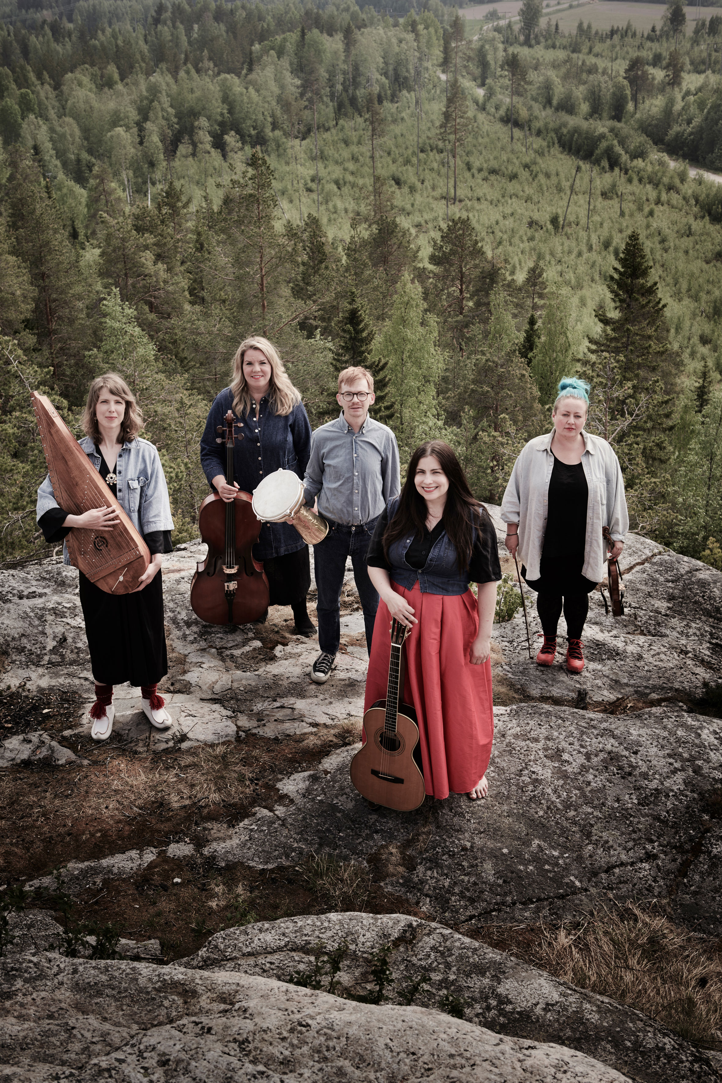 Grupp på bilderna som medverkar i konserten Utsikt från ett berg. Musikerna står uppe på ett berg. I bakgrunden ser man skog och himmel. 