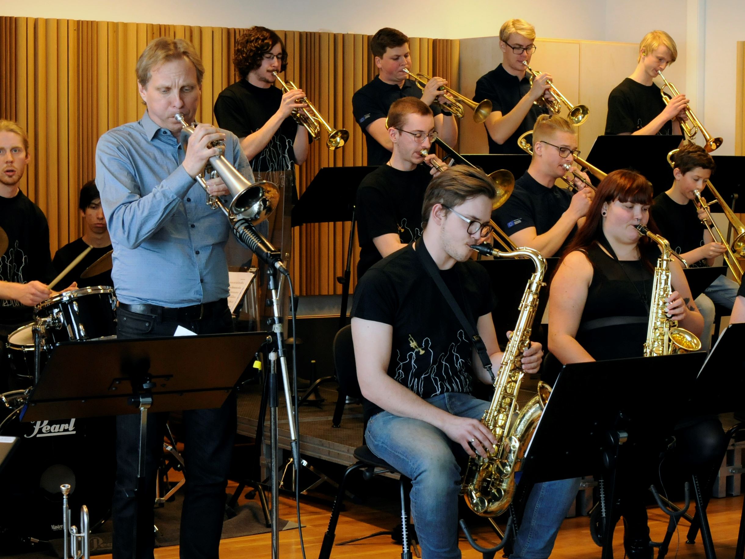 14 unga musiker i ett ungdomsstorband som sitter och repeterar, solist på trumpet som s...