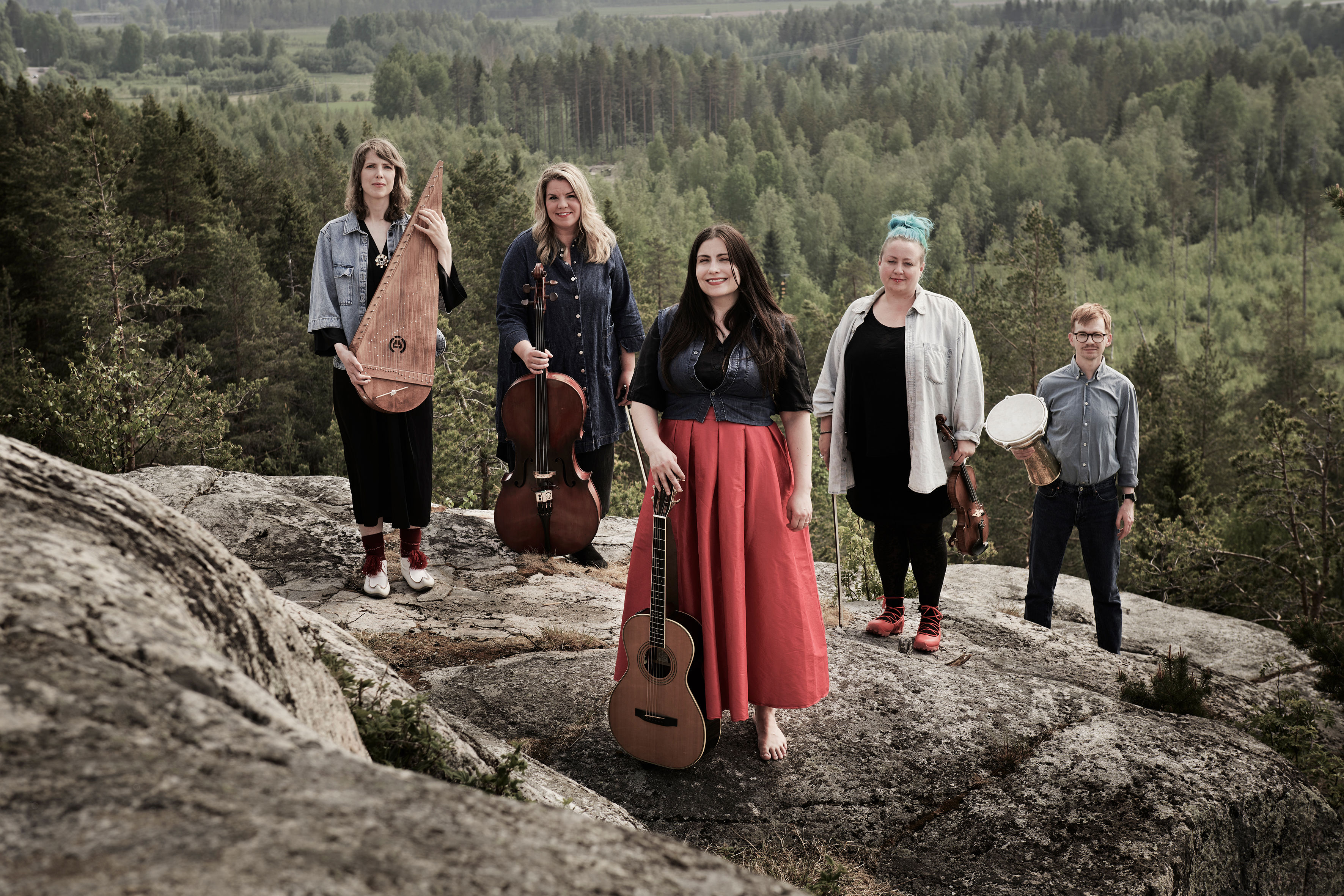 Grupp på bilderna som medverkar i konserten Utsikt från ett berg. Musikerna står uppe på ett berg. I bakgrunden ser man skog och himmel. 