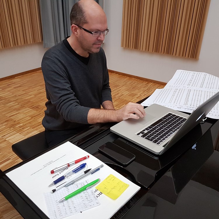 Daniel Saur sitter vid pianot och komponerar musik med hjälp av en bärbar dat...