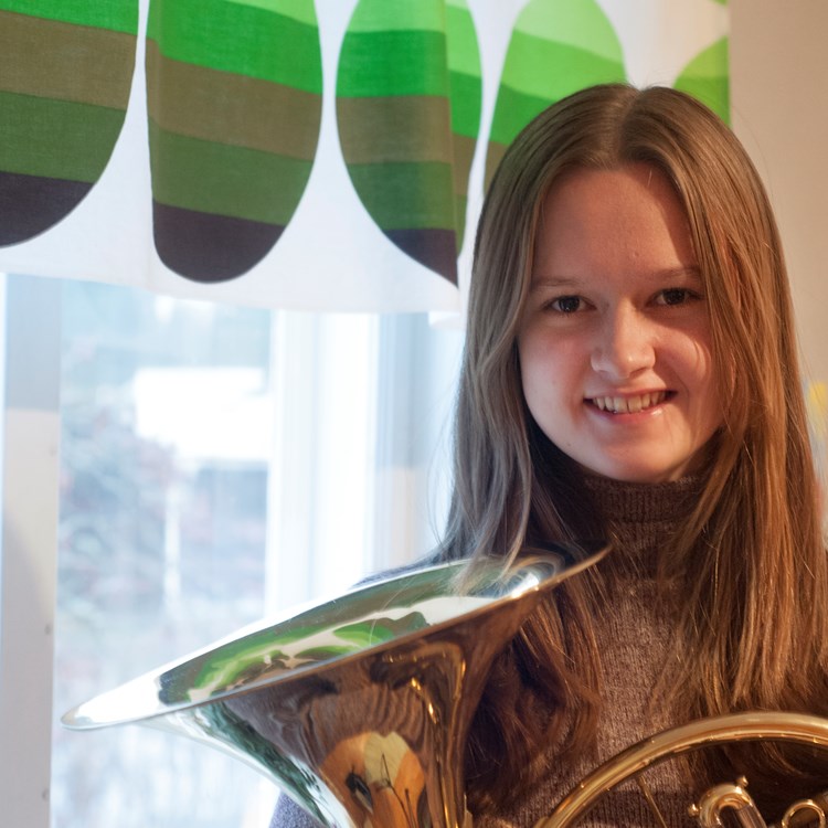 Ungdomssymfonikern Rebecca Hellgren står vid ett fönster med sitt instrument i famnen