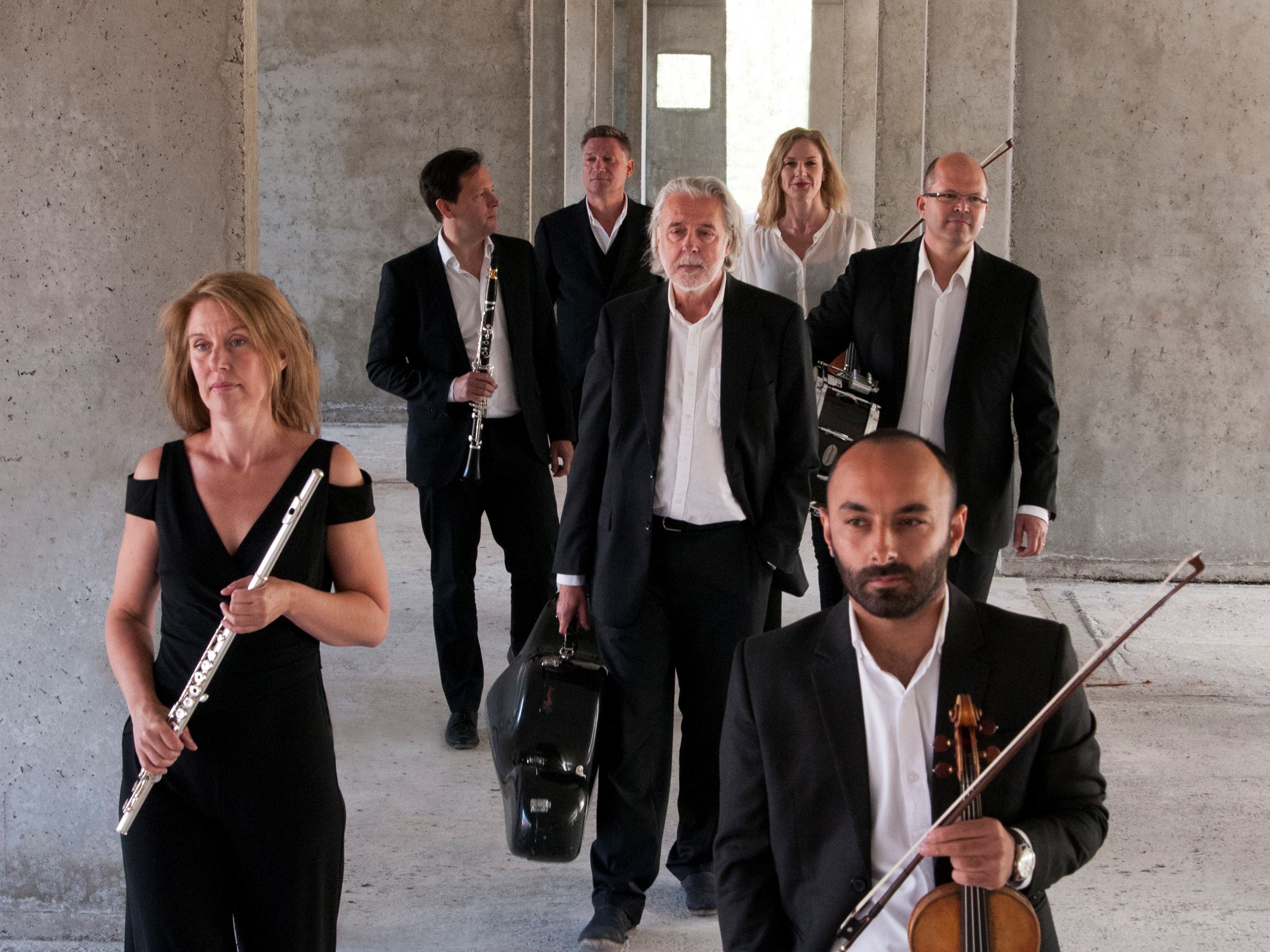 Musikerna i ensemblen Norrbotten NEO kommer gående med sina musikinstrument i en betong...