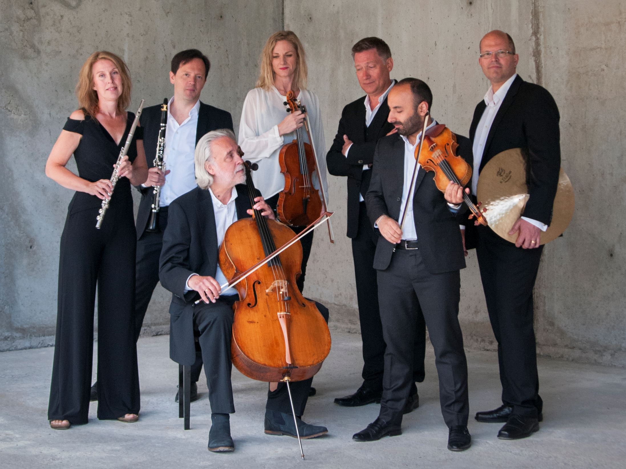 Musikerna i ensemblen Norrbotten NEO står eller sitter med sina musikinstrument i en be...