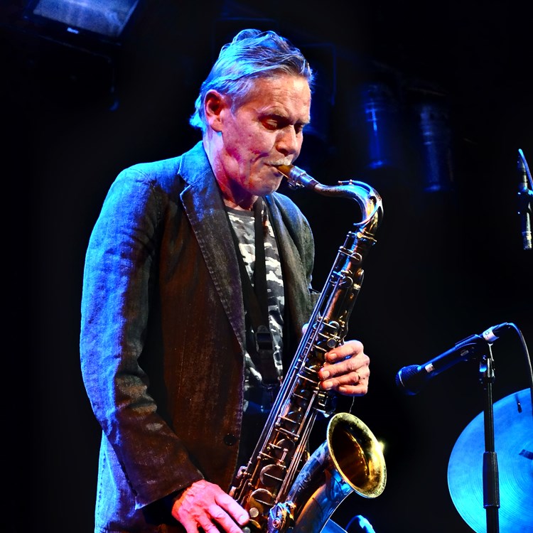 Musikern Krister Andersson står på scen och spelar saxofon.