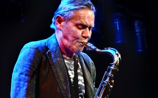 Musikern Krister Andersson står på scen och spelar saxofon.