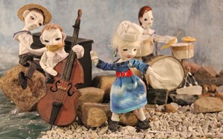 På bilden är det fyra dockor. Tre av dem spelar instrument och en sjunger.