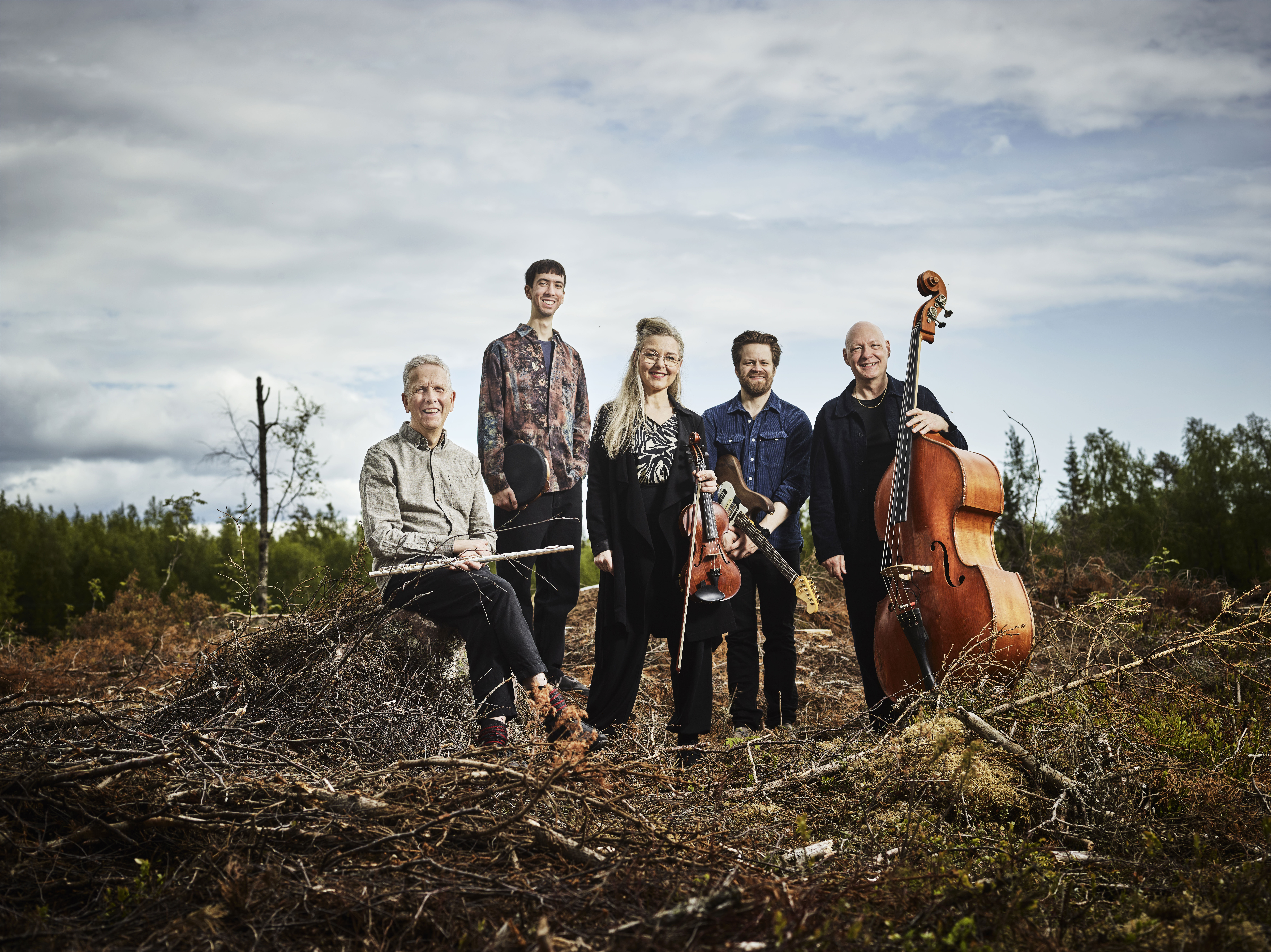 Gruppbild på Erling Fredriksson och hans musiker där dom står ute med sina instrument på ett kalhygge. 