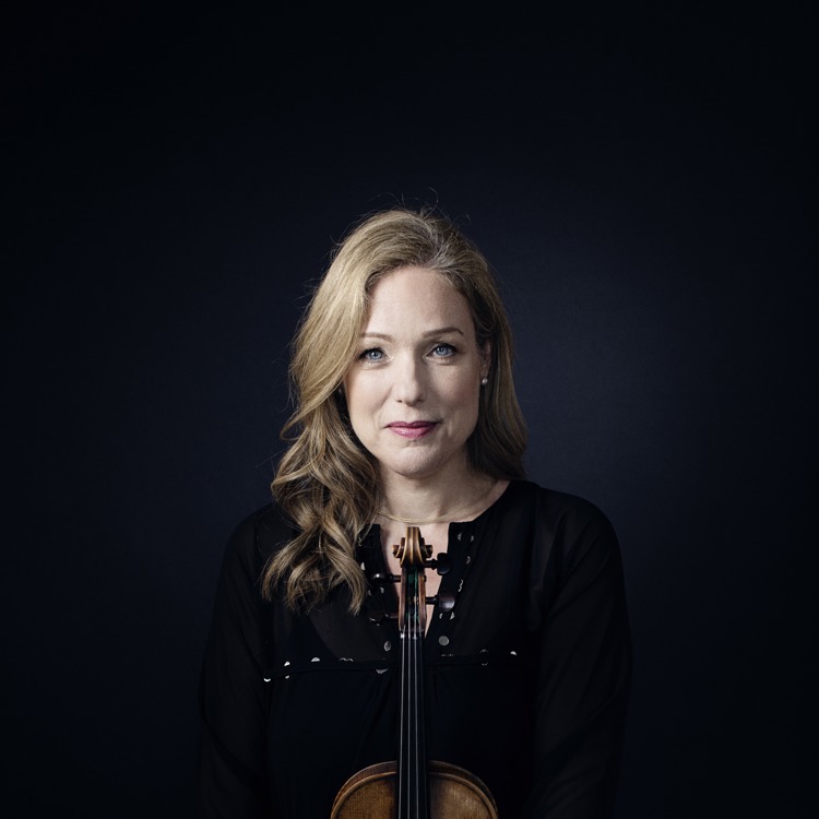 Porträttbild på violinisten Isabelle van Keulen hållandes i en violin. Bakgrunden är mörkblå och svart.