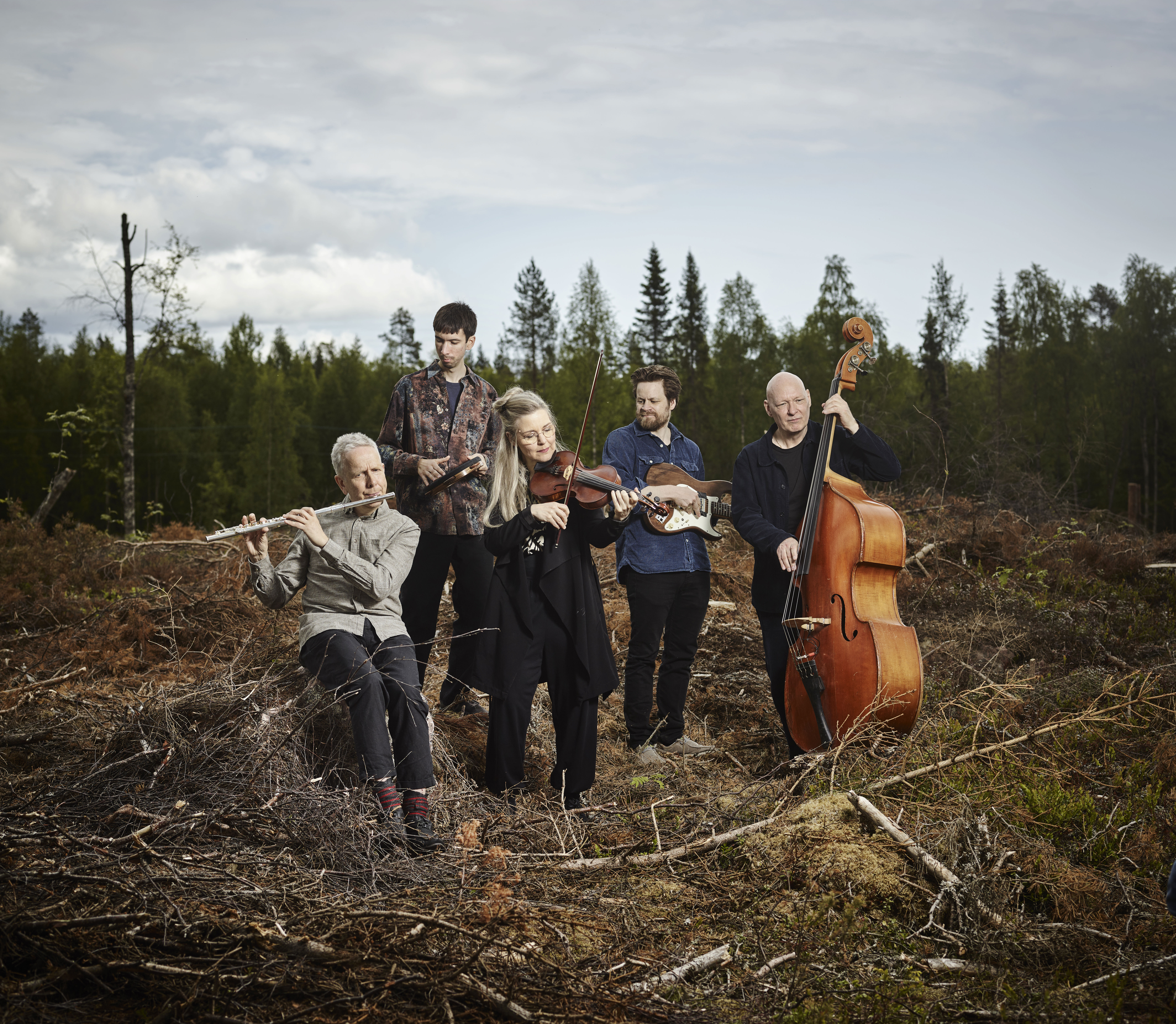 Gruppbild på Erling Fredriksson och hans musiker där dom står ute och spelar på ett kalhygge. 