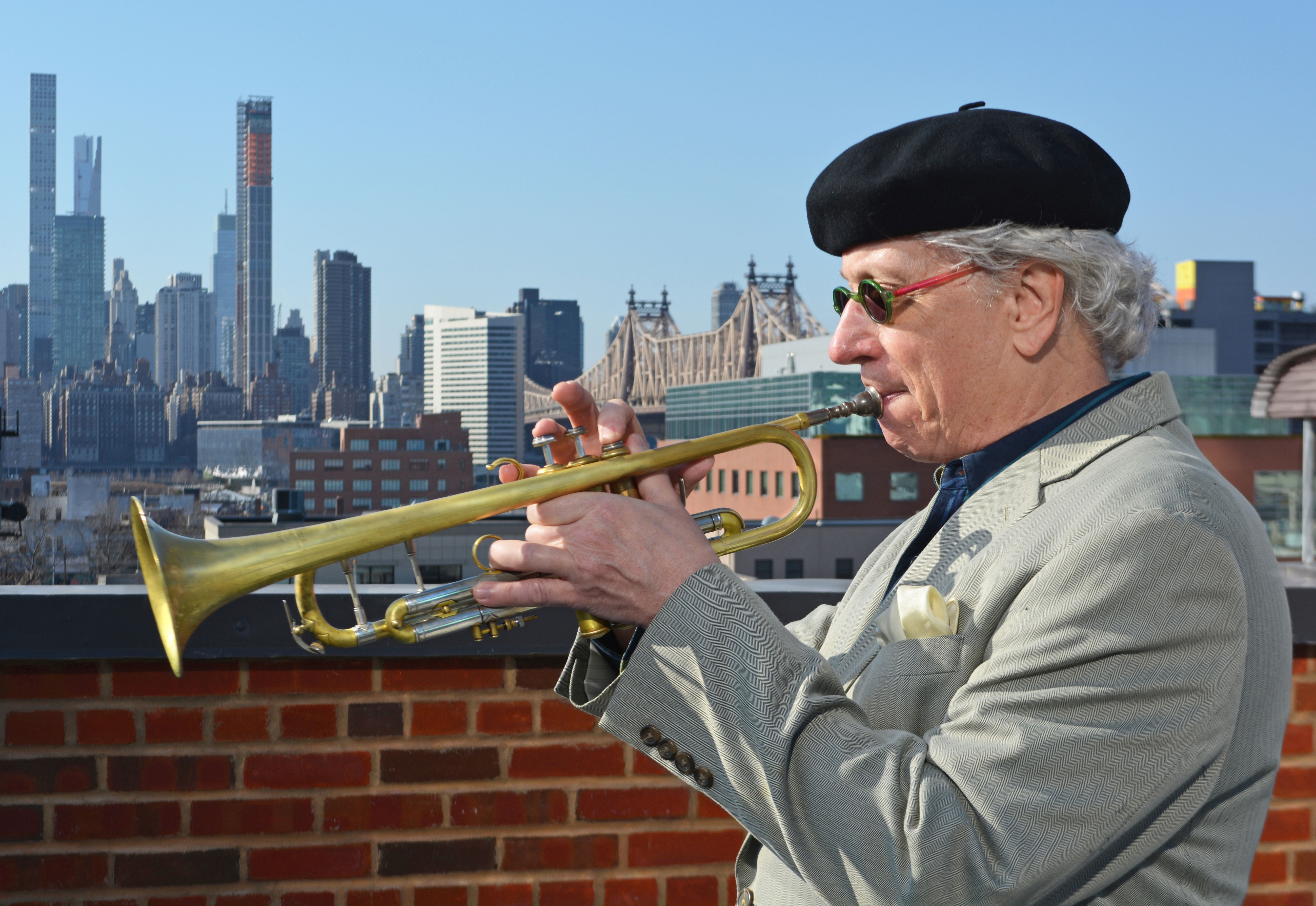 Bild på trumpetaren och kompositören Tim Hagans när han spelar på en trumpet. I bakgrunden syns siluetten av New York.