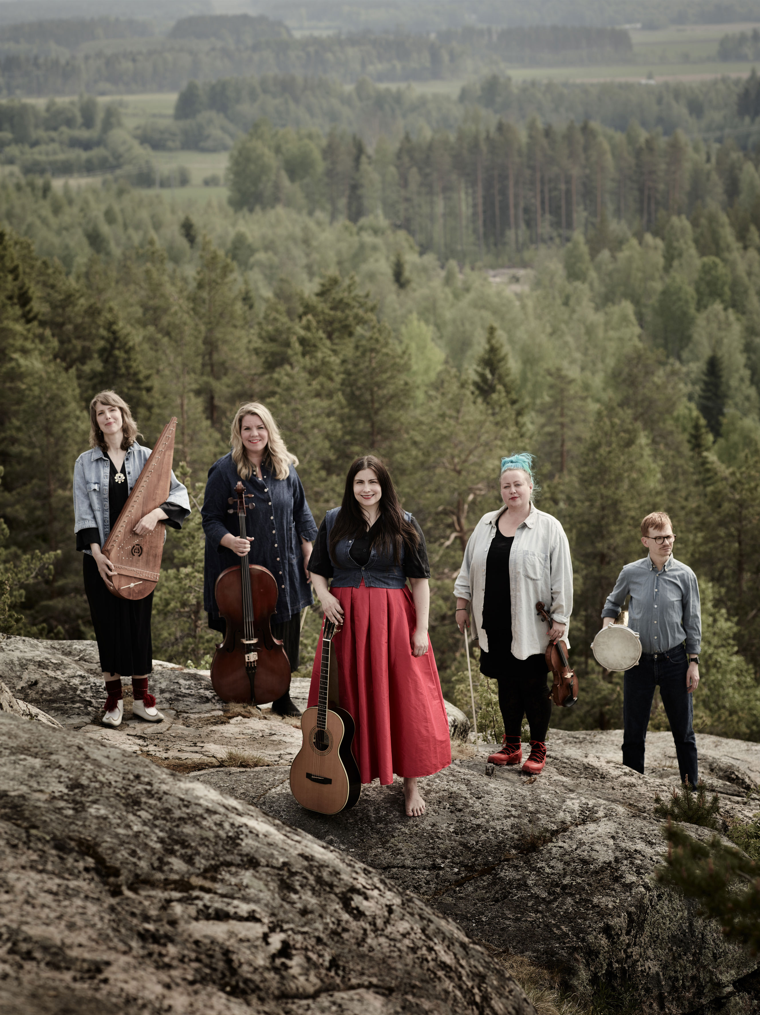 Grupp på bilderna som medverkar i konserten Utsikt från ett berg. Musikerna står uppe på ett berg. I bakgrunden ser man skog och himmel. 