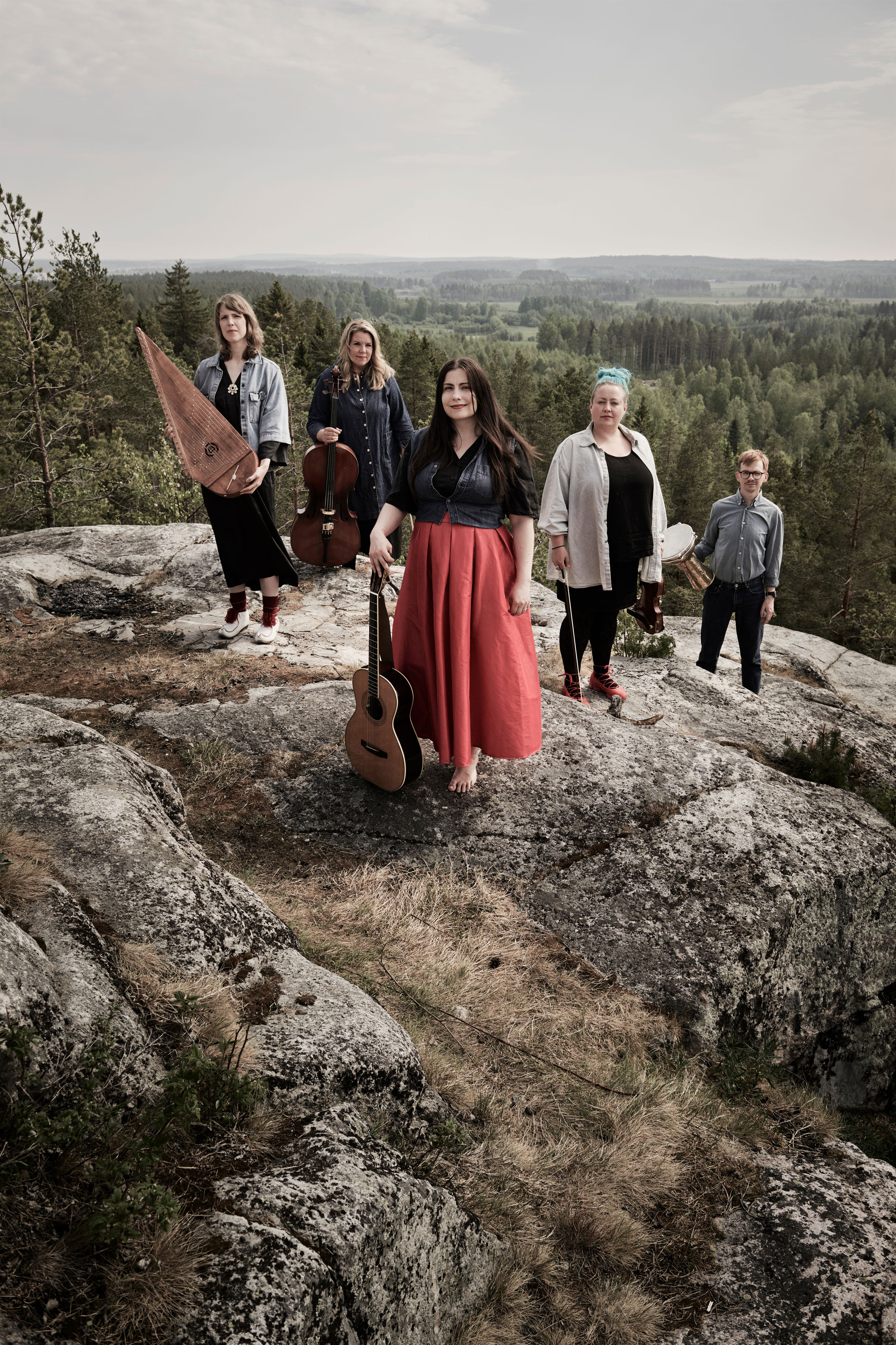 Grupp på bilderna som medverkar i konserten Utsikt från ett berg. Musikerna står uppe på ett berg. I bakgrunden ser man skog och himmel. 